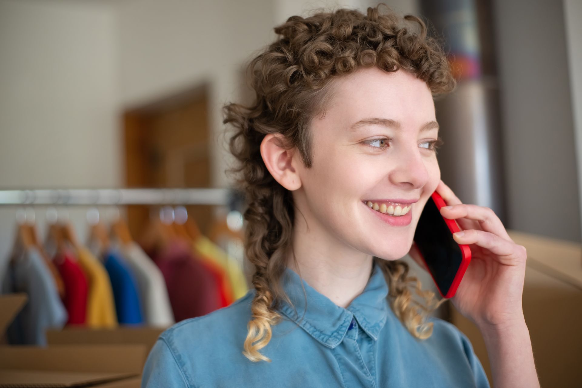 Smiling woman making a phone call in a bright indoor setting with blurred background.