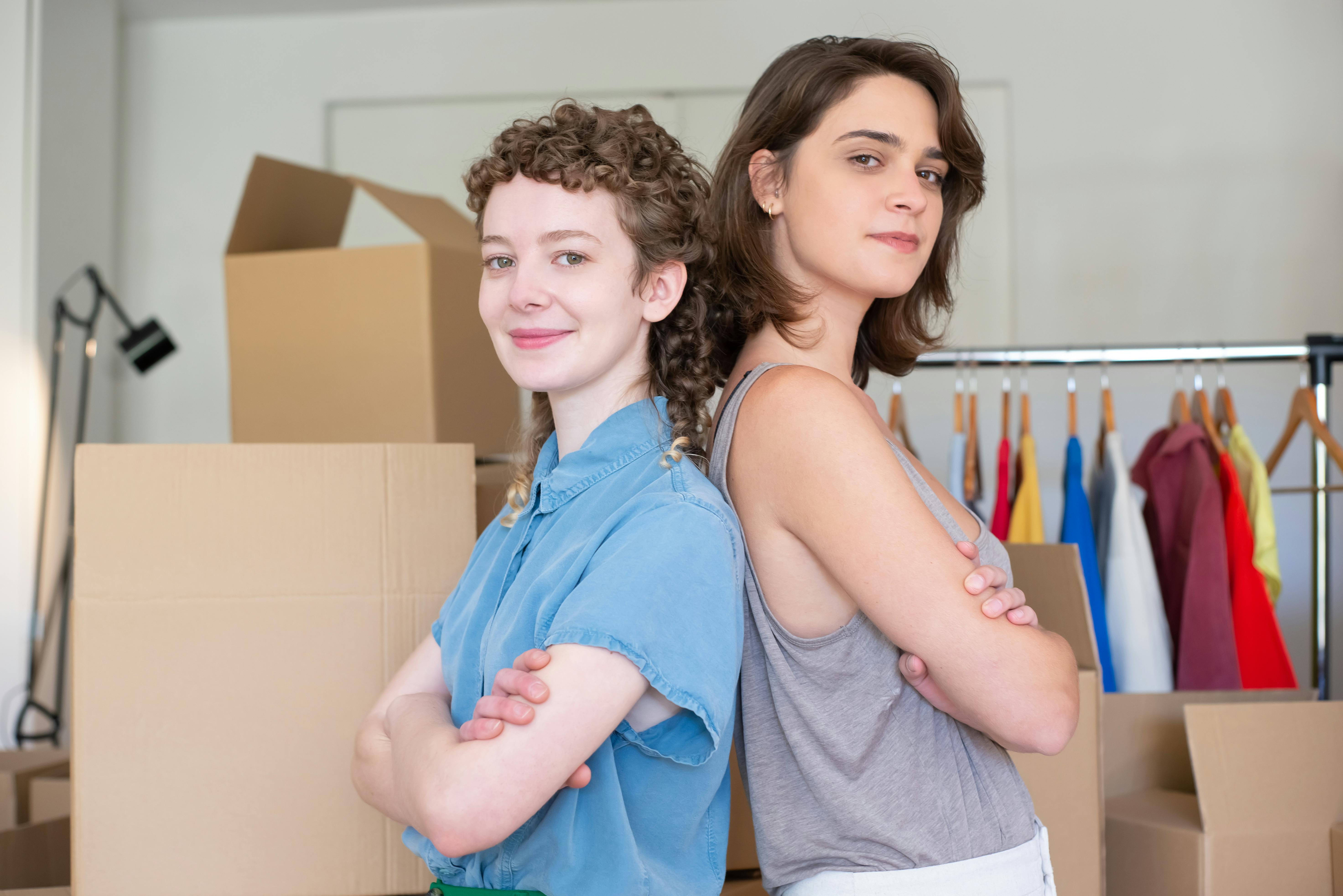 a woman in blue button up shirt standing beside a woman in gray tank top