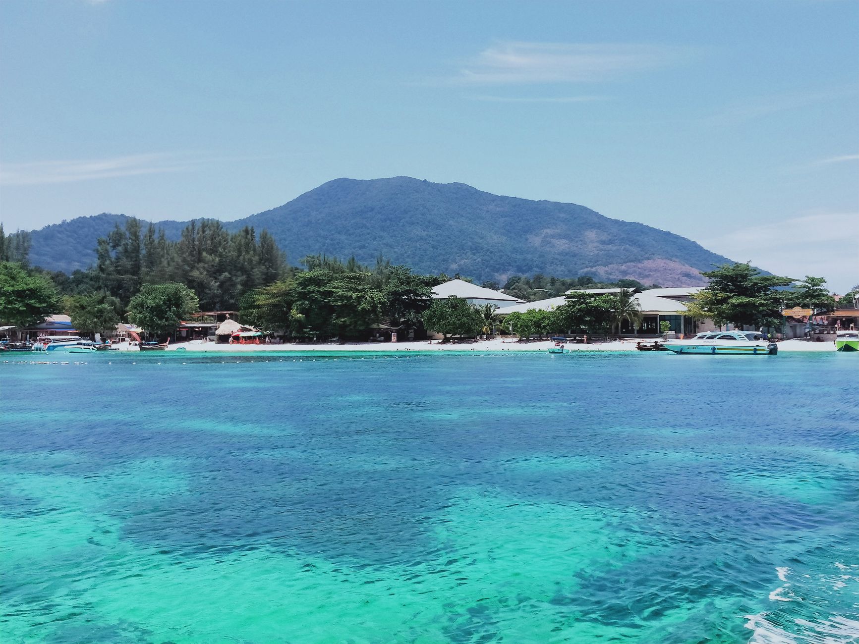 Crystal-clear waters and lush mountains in Satun, Thailand offer a stunning tropical retreat.