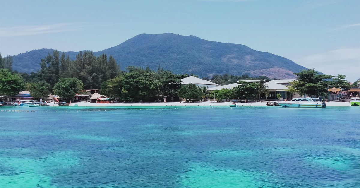 Crystal-clear waters and lush mountains in Satun, Thailand offer a stunning tropical retreat.