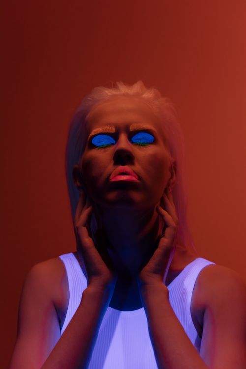Free Artistic portrait of a woman with vibrant makeup under neon lighting in a studio setting. Stock Photo
