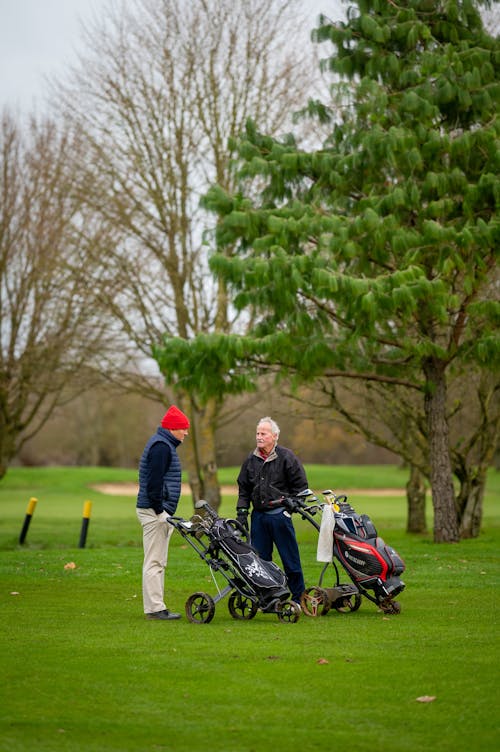 Free Elderly Men Talking near Golf Bags on the Grass Field Stock Photo