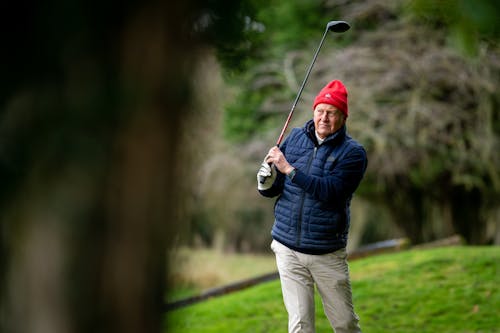 Free Elderly Man in Red Winter Hat Holding Golf Stick Stock Photo