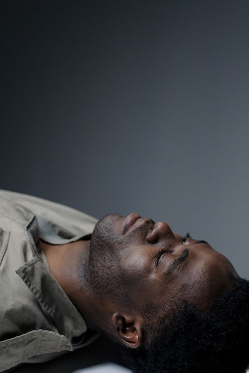 Free Peaceful portrait of a black man lying down with eyes closed in a studio setting. Stock Photo