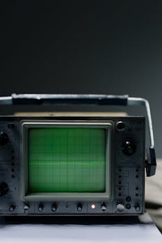 Close-up of a vintage oscilloscope showing a green waveform on a grid screen.