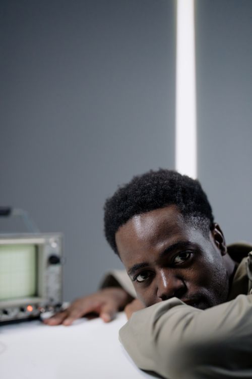 Free Pensive African American man resting on a table with a vintage device in a studio setting. Stock Photo