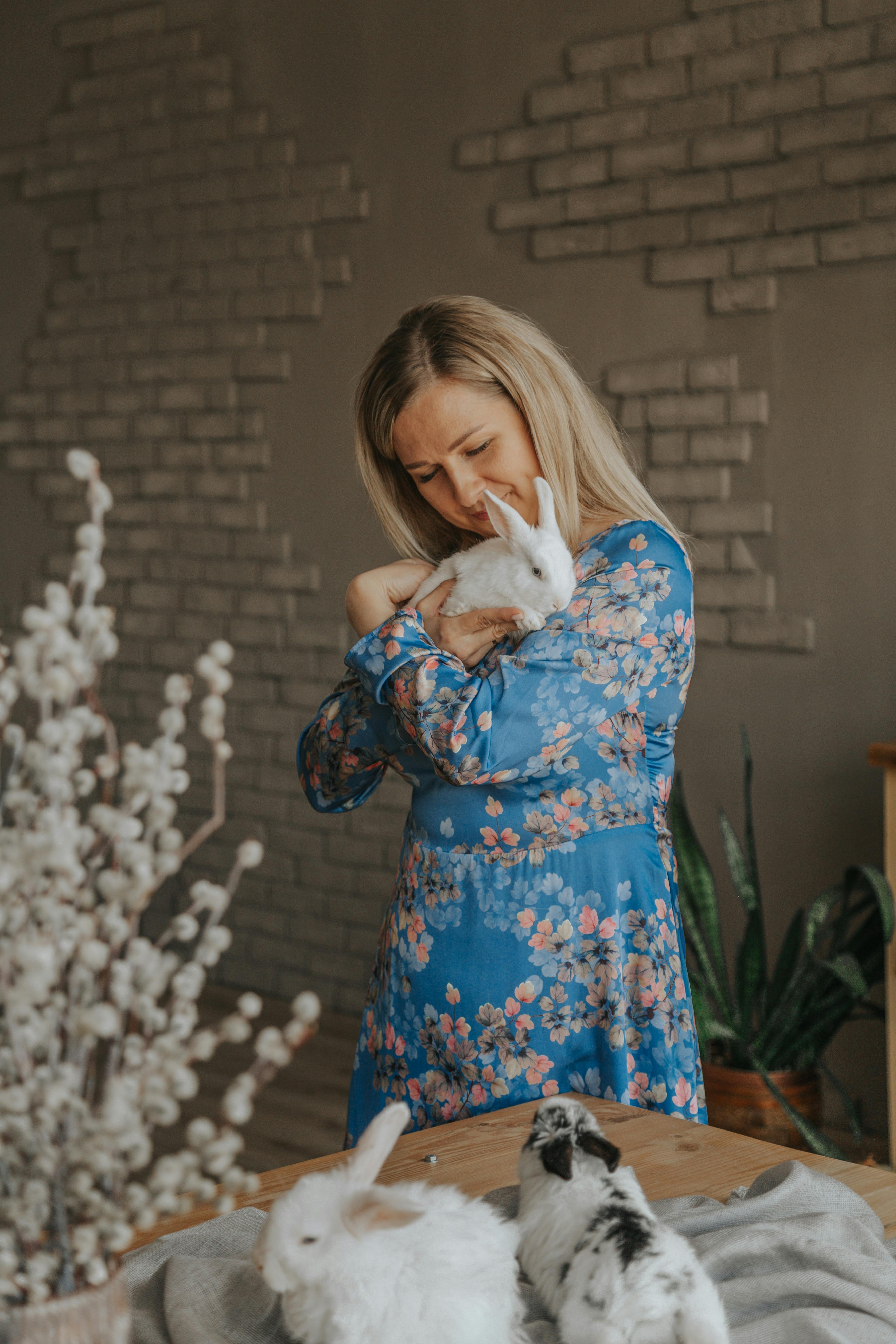 smiling woman embracing rabbit in house room