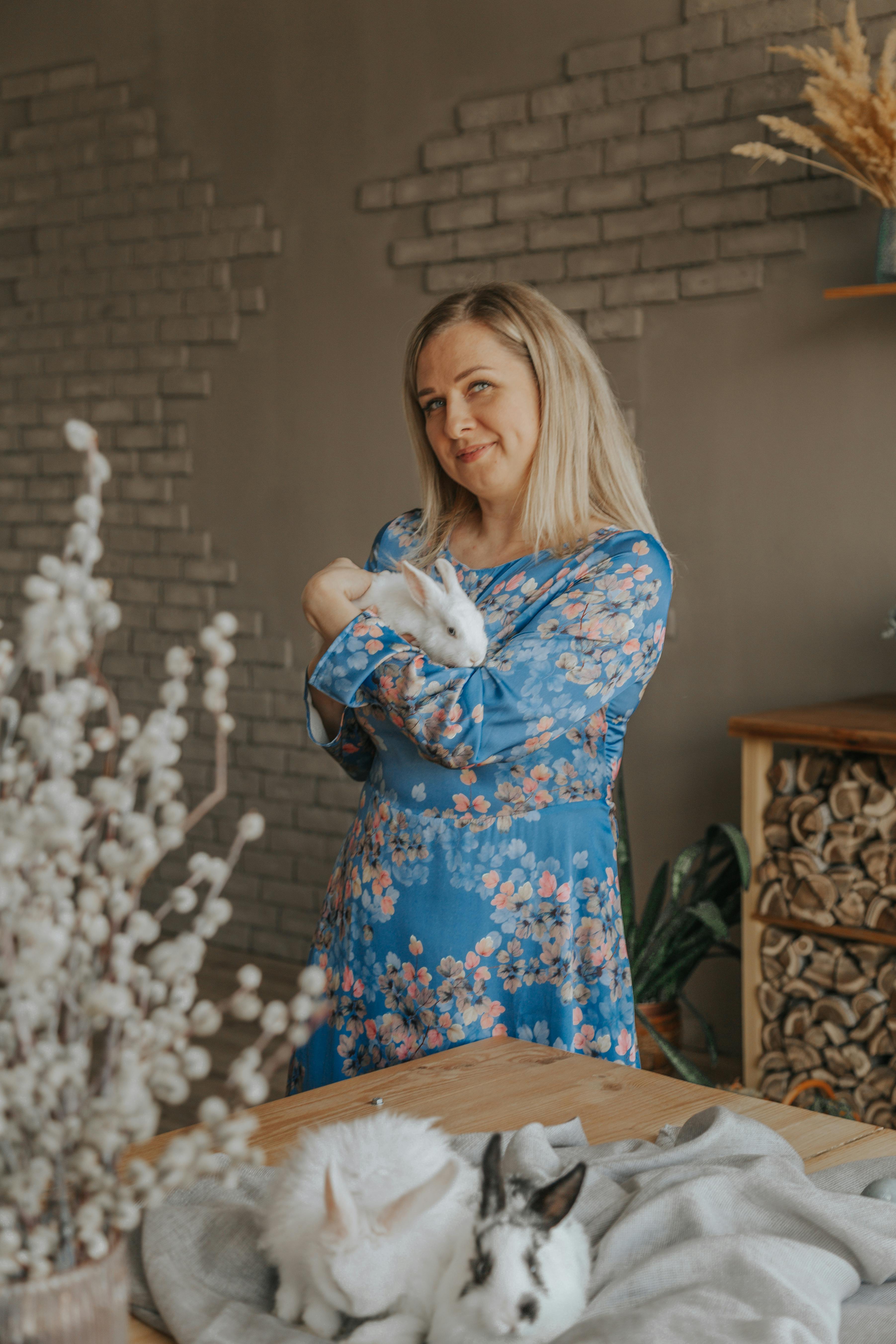 smiling woman embracing cute rabbit at home