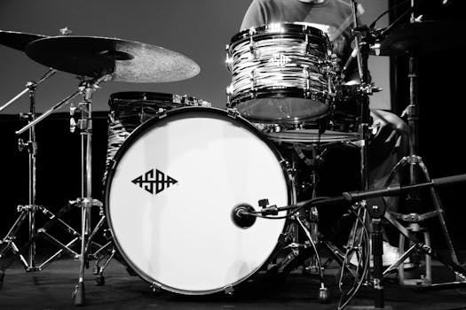 Black and white close-up of a drum set with a logo, captured in a studio setting.