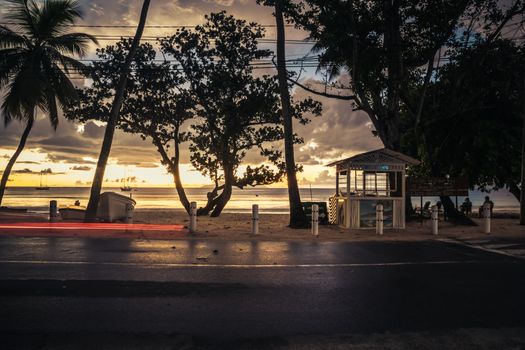 A tranquil sunset scene with silhouetted trees and a hut on a Seychelles beach.