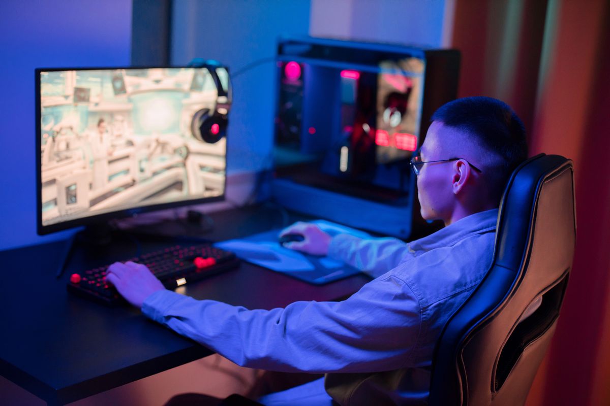 Gamer at PC with headphones in a dark gaming setup