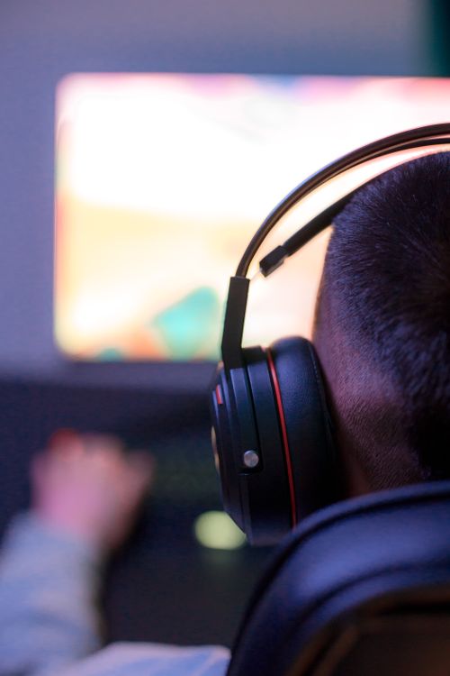 Free A young man with headphones playing video games on a computer, showcasing intense concentration. Stock Photo