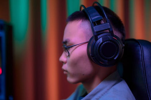 Side view of a serious gamer wearing headphones and eyeglasses indoors.