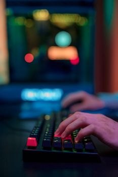 Close-up of hands typing on RGB-lit gaming keyboard with a colorful bokeh background.