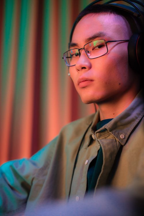 Free Portrait of a serious man wearing glasses and headphones, set against colorful curtains Stock Photo