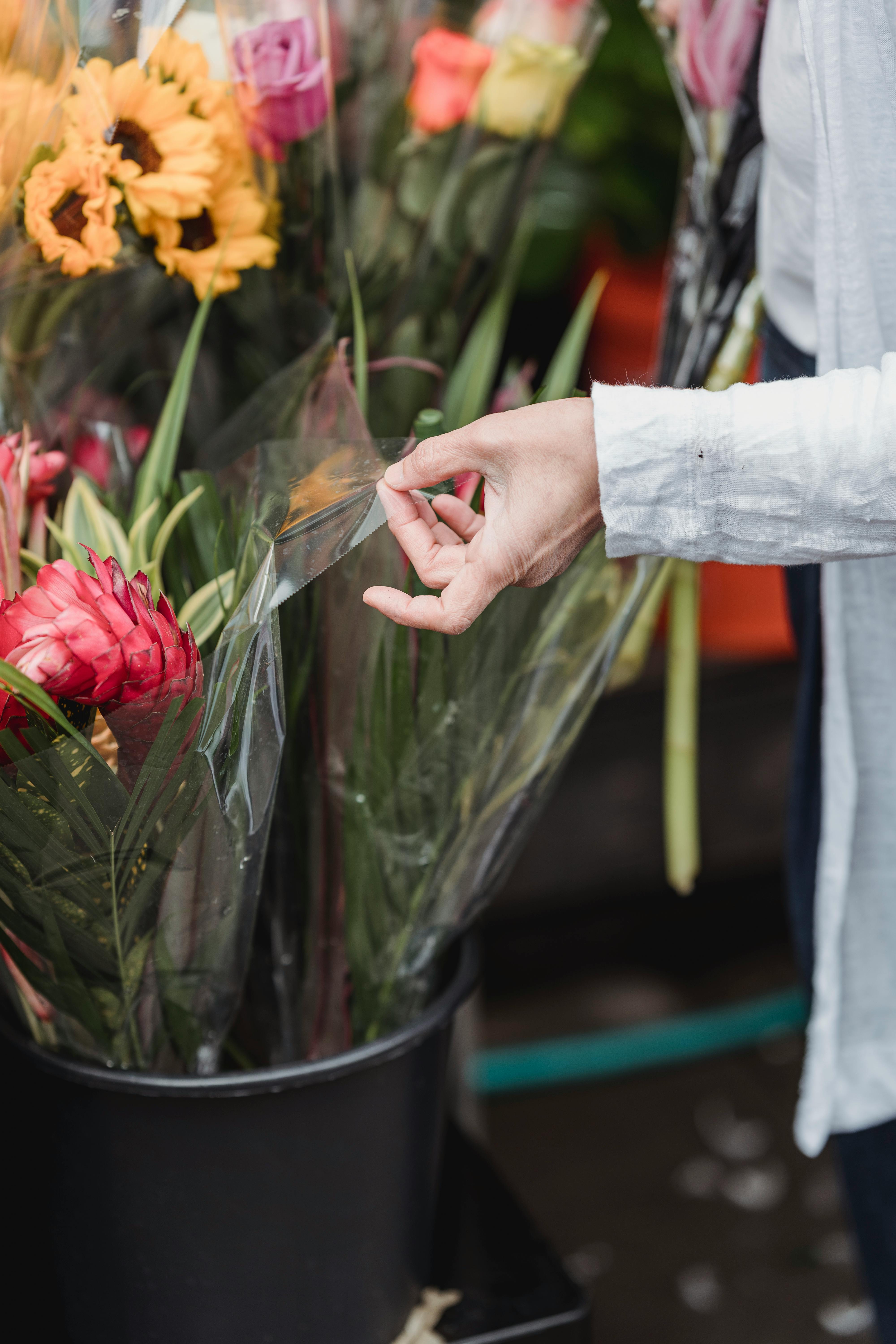[ColoSach]-a-close-up-of-a-hand-selecting-vibrant-bouquets-wrapped-in-plastic-at-a-flower-market.