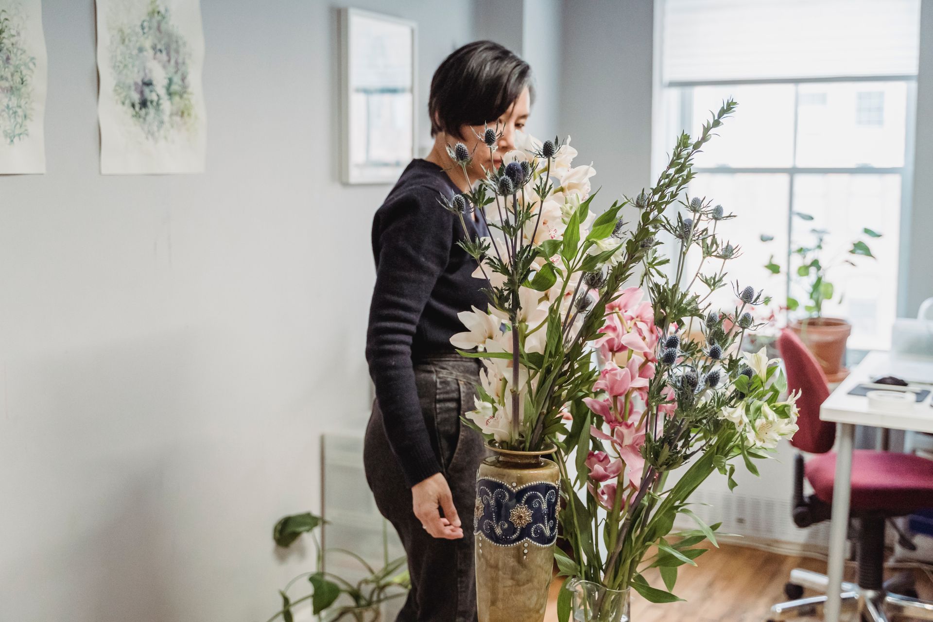A florist arranges a vibrant bouquet of flowers in a stylish indoor space.