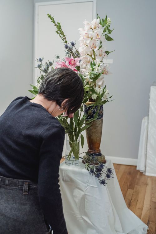 Arranging a tall vase of flowers indoors — photo by Greta Hoffman on Pexels