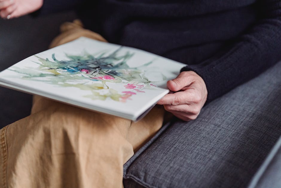 A person holds a watercolor sketchbook with vibrant botanical artwork.