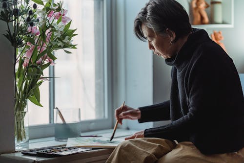 A Woman Painting an Artwork in a Sketchpad