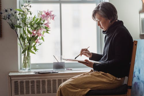 A Woman Painting an Artwork in a Sketchpad