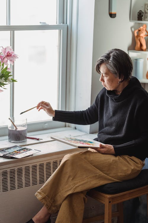 A Woman Painting an Artwork in a Sketchpad