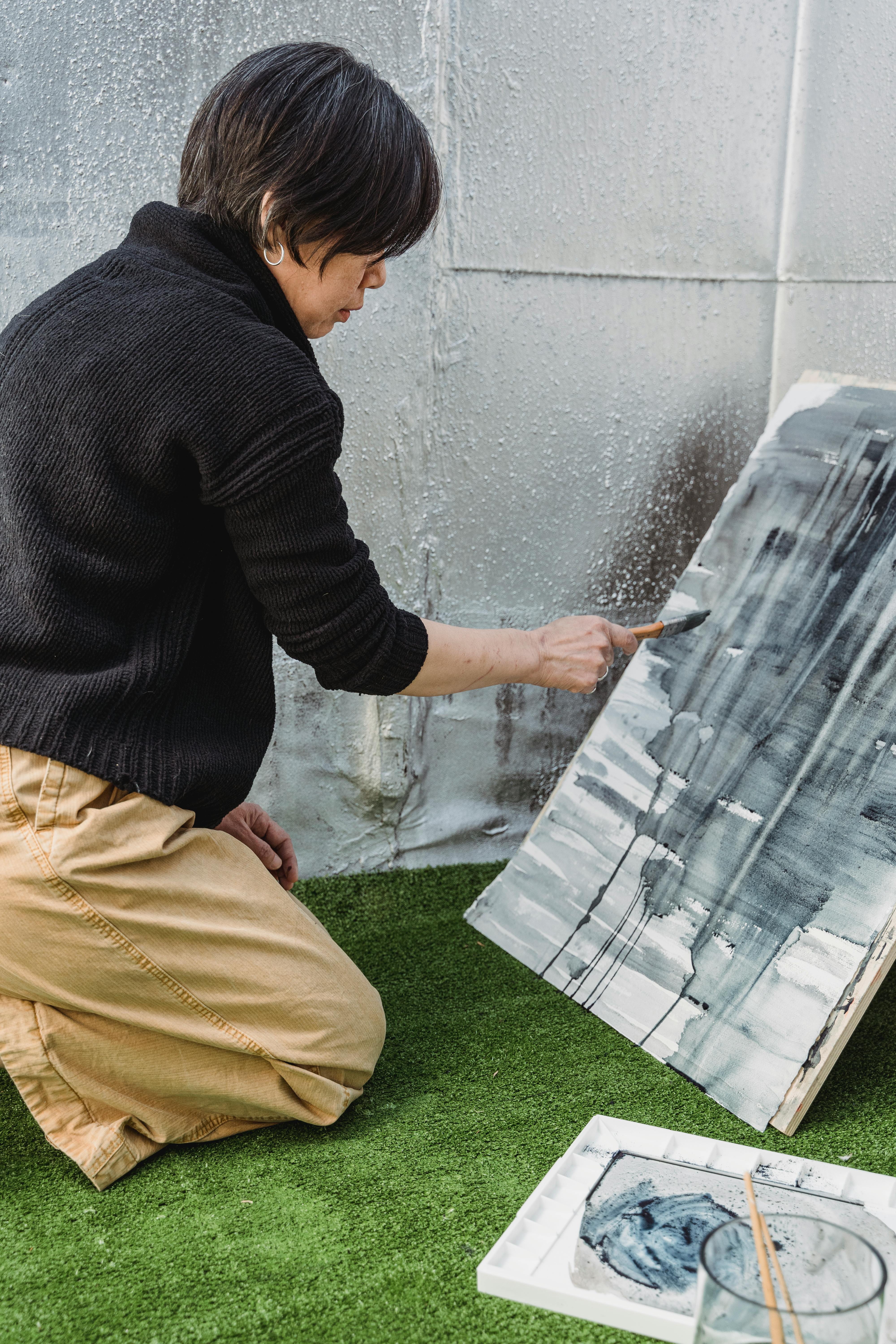 A person creating abstract art using a brush on a canvas indoors.