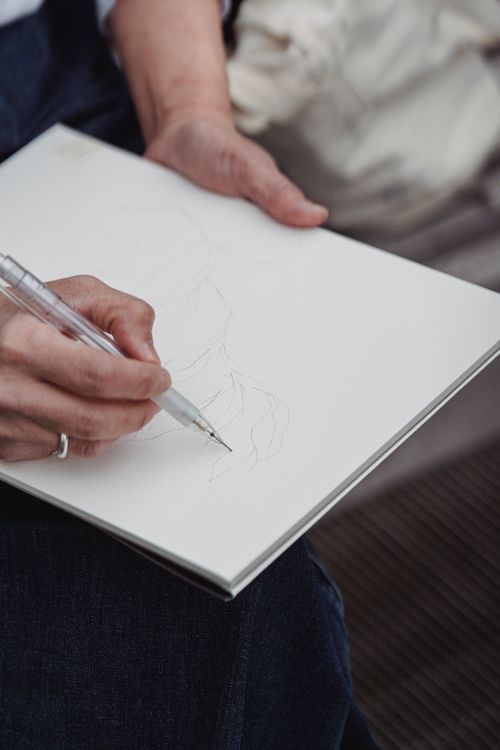 Free Person's hand drawing on a sketchpad, capturing creativity in indoor setting. Stock Photo
