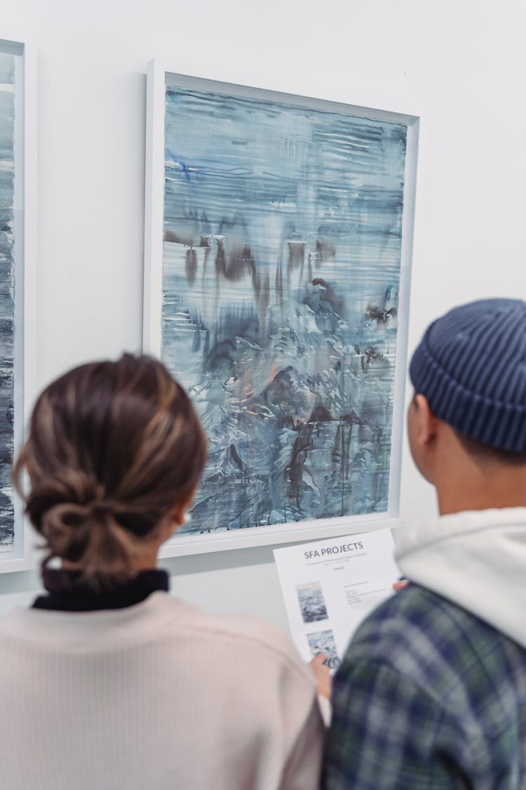 Man And Woman Standing Near The Abstract Paintings Hanged On The Wall