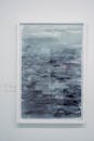 蓝色色调的垂直抽象绘画，以海景为主题，框架在白色的墙上