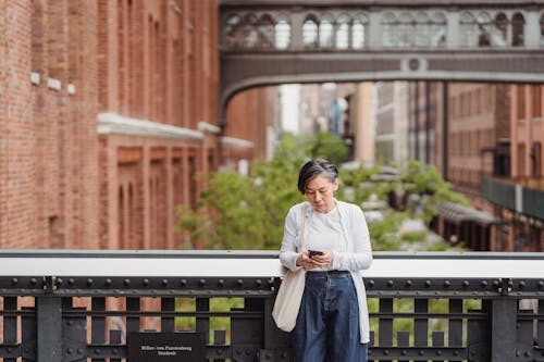 Woman Leaning on the Railings while Using a Smartphone
