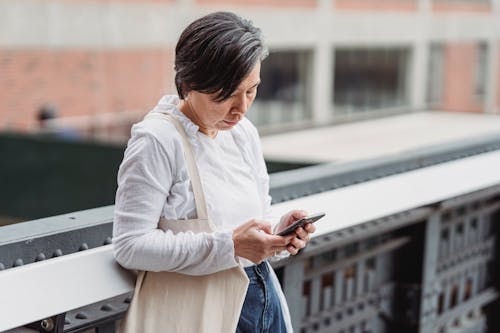 Akıllı Telefon Kullanırken Korkuluklara Yaslanan Kadın