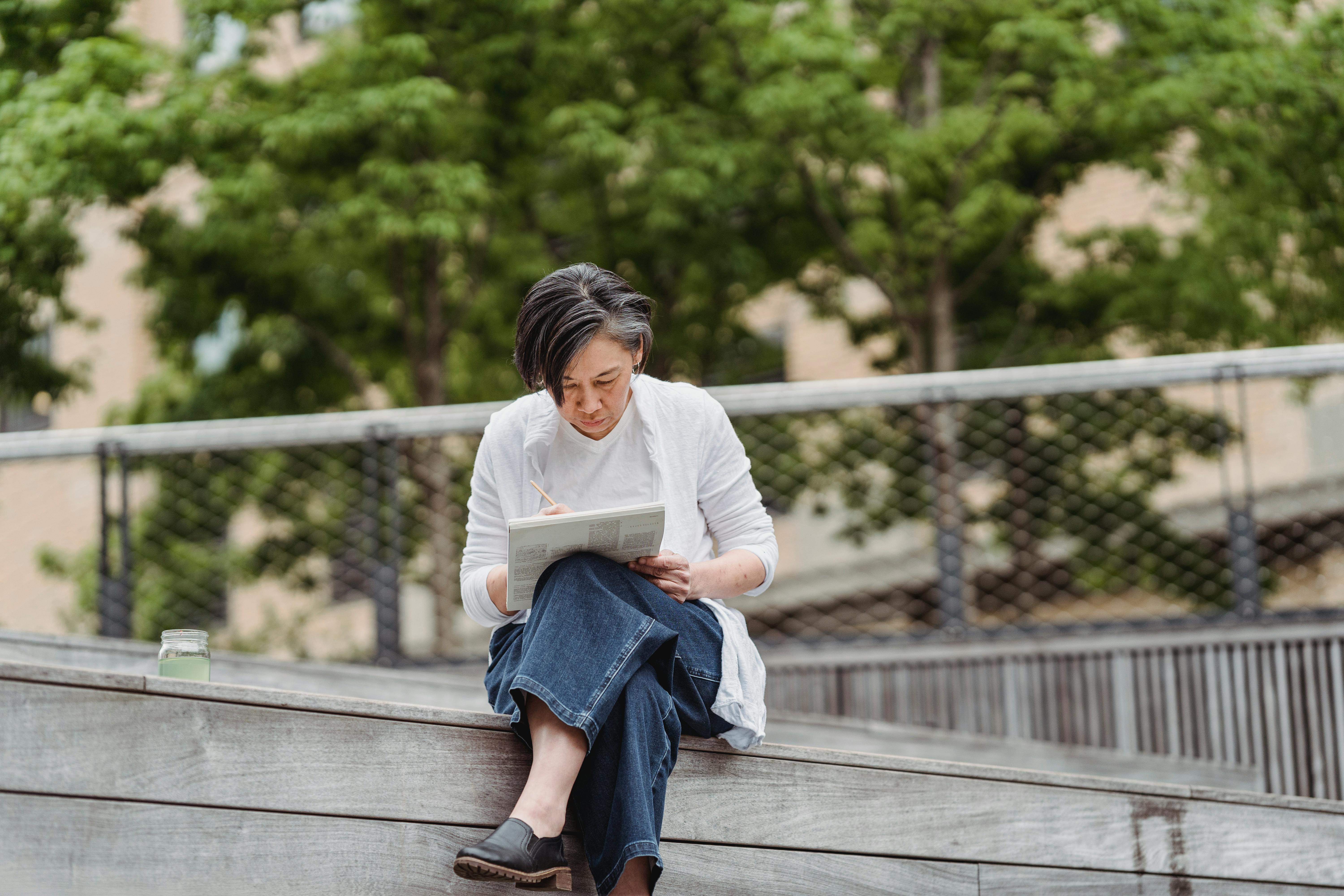 a woman sitting alone while writing on a book