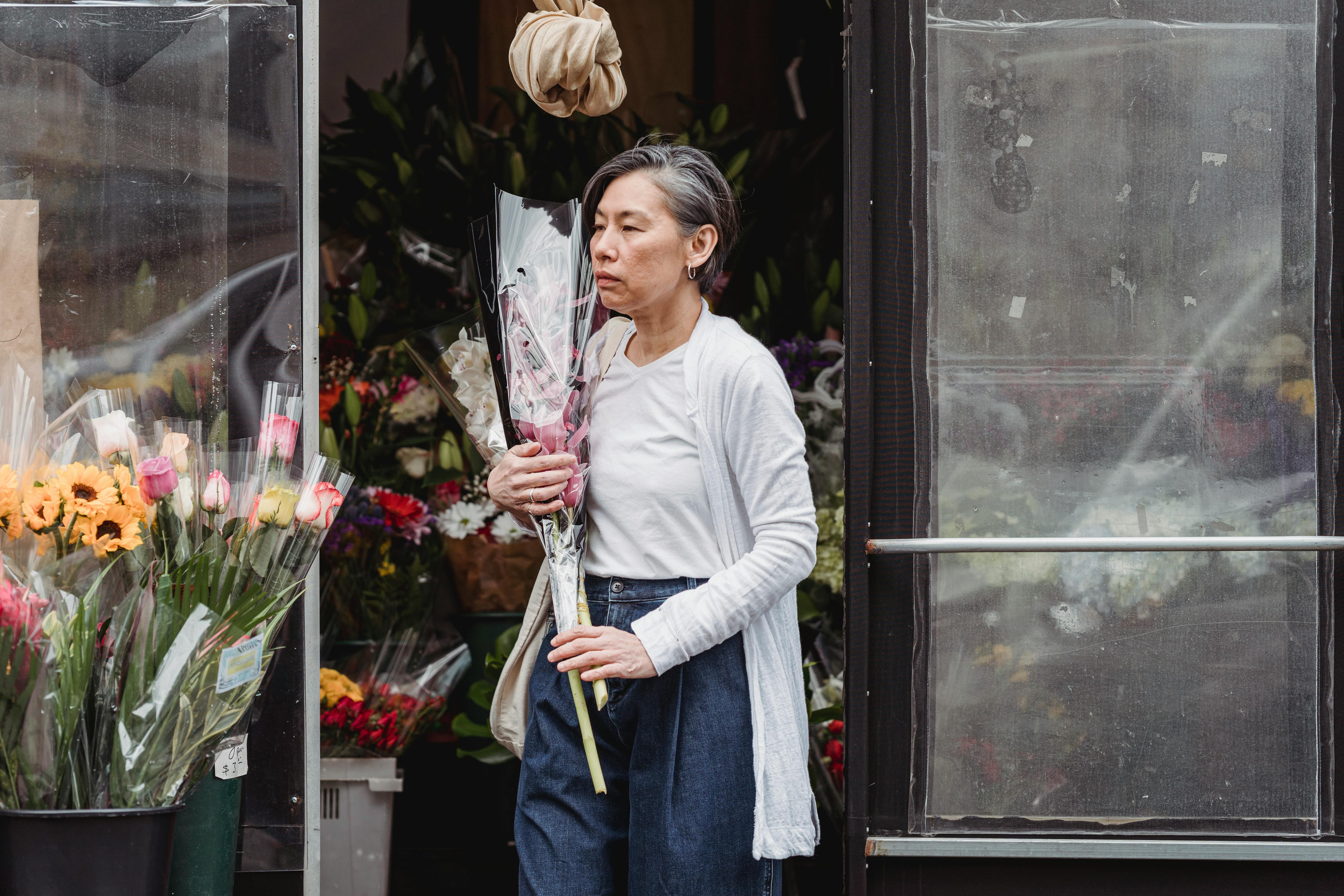Woman in White Cardigan Holding Bouquet of Flowers