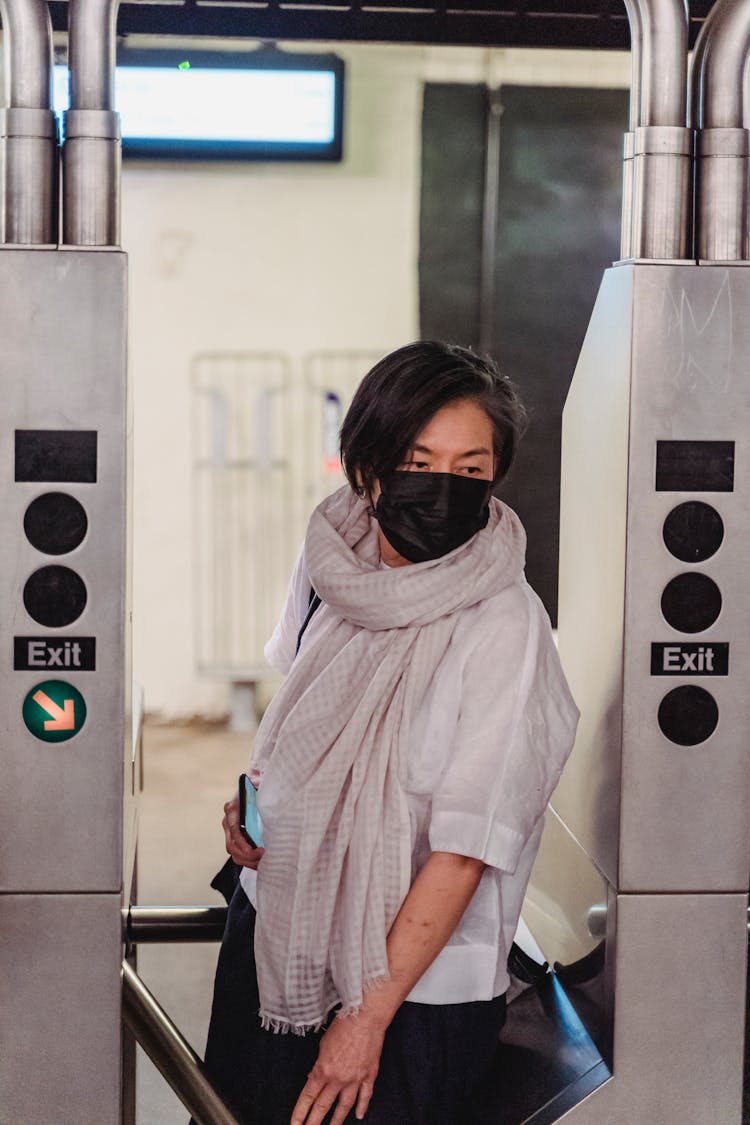 A Woman Passes Through A Turnstile At A Train Station