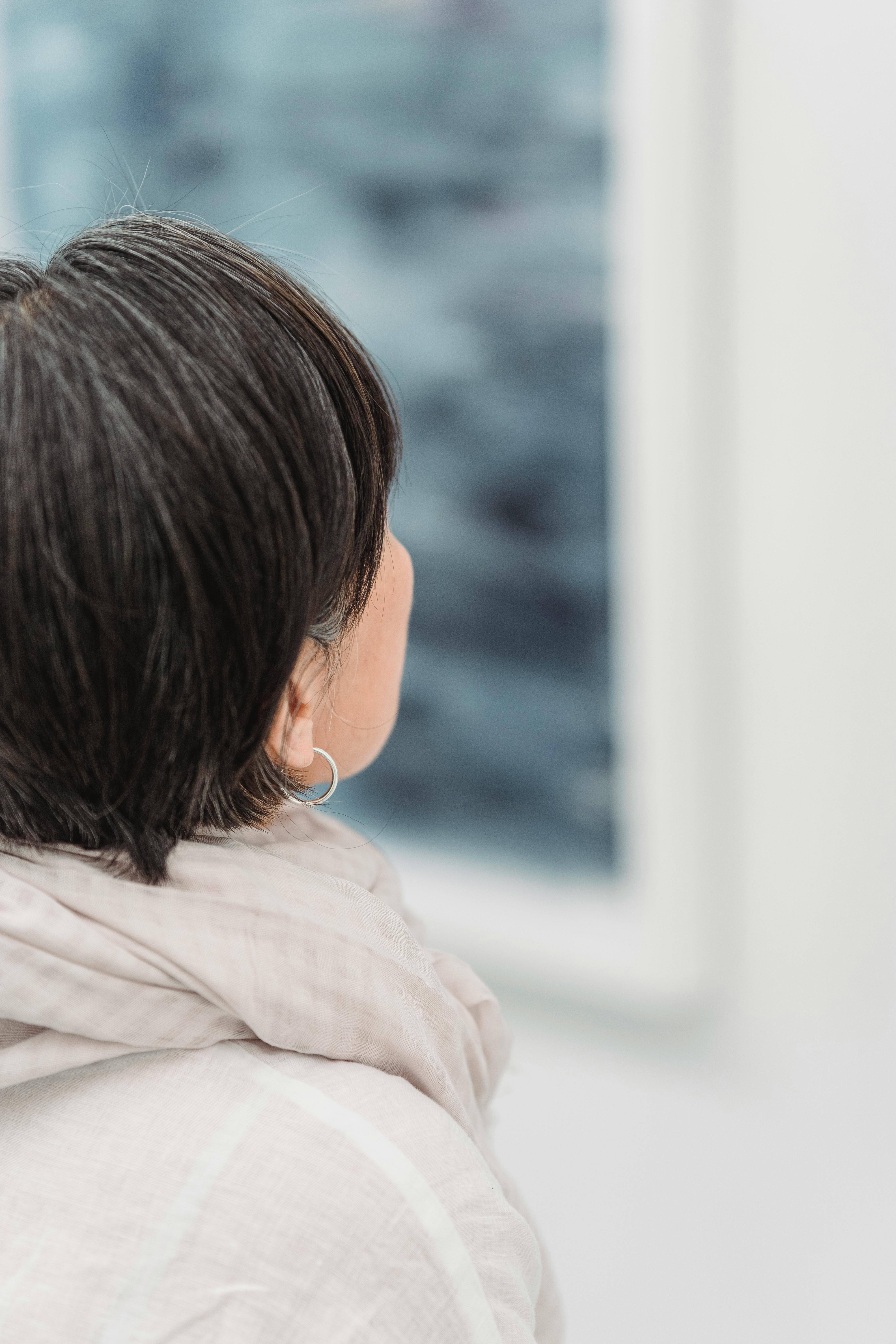 A woman with short hair gazes at artwork in a contemporary gallery space.