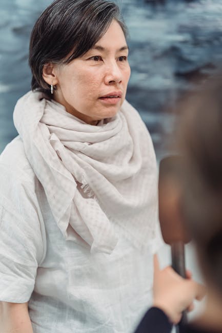 A woman in a light scarf participates in an interview indoors, captured during the day.