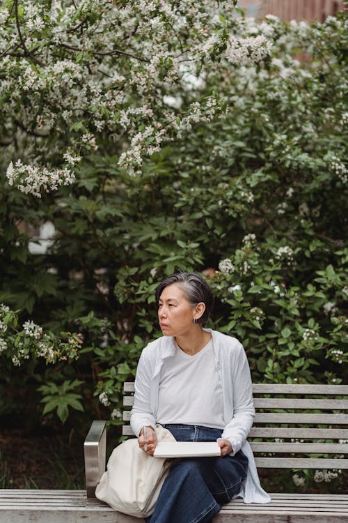 Woman in White Long Sleeve Shirt Sitting on a Bench
