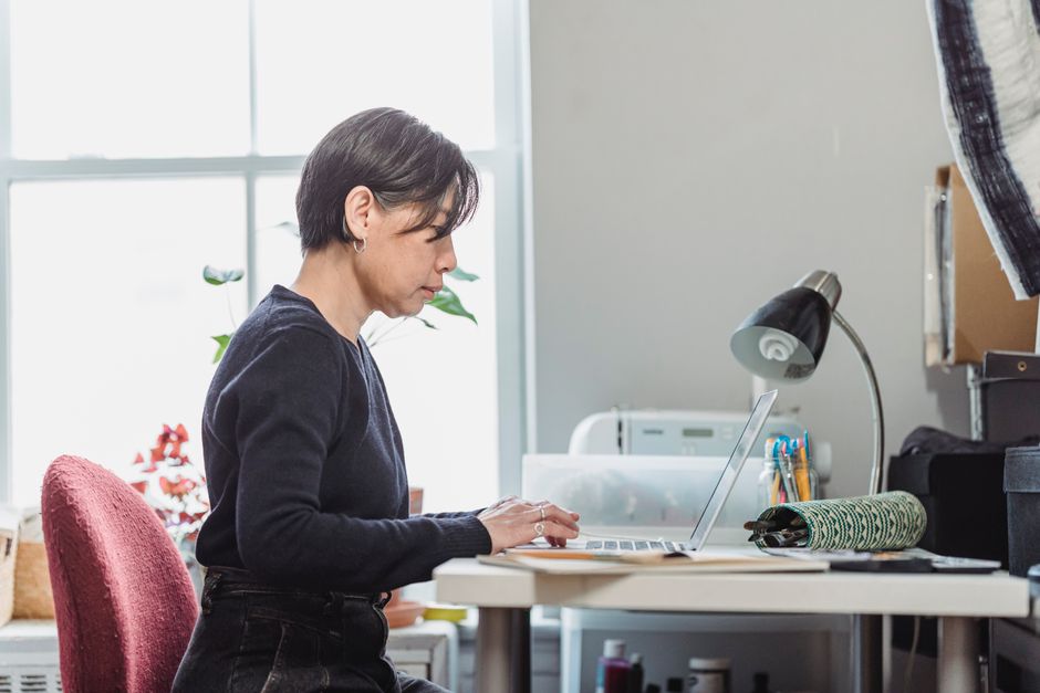 A woman remotely working on a laptop from a home office, showcasing a focused work environment.