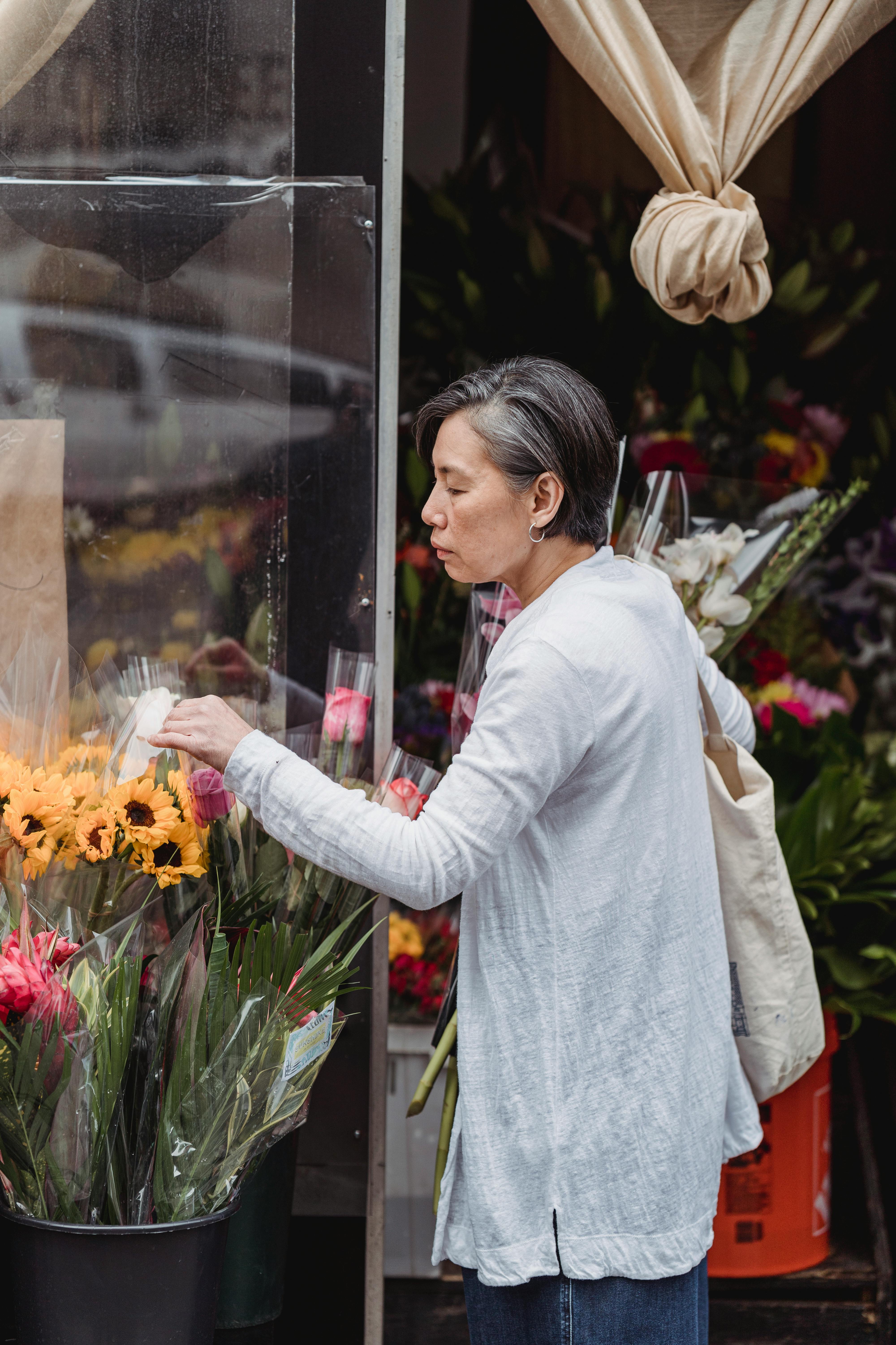 woman in white long sleeve shirt holding bouquet of flowers