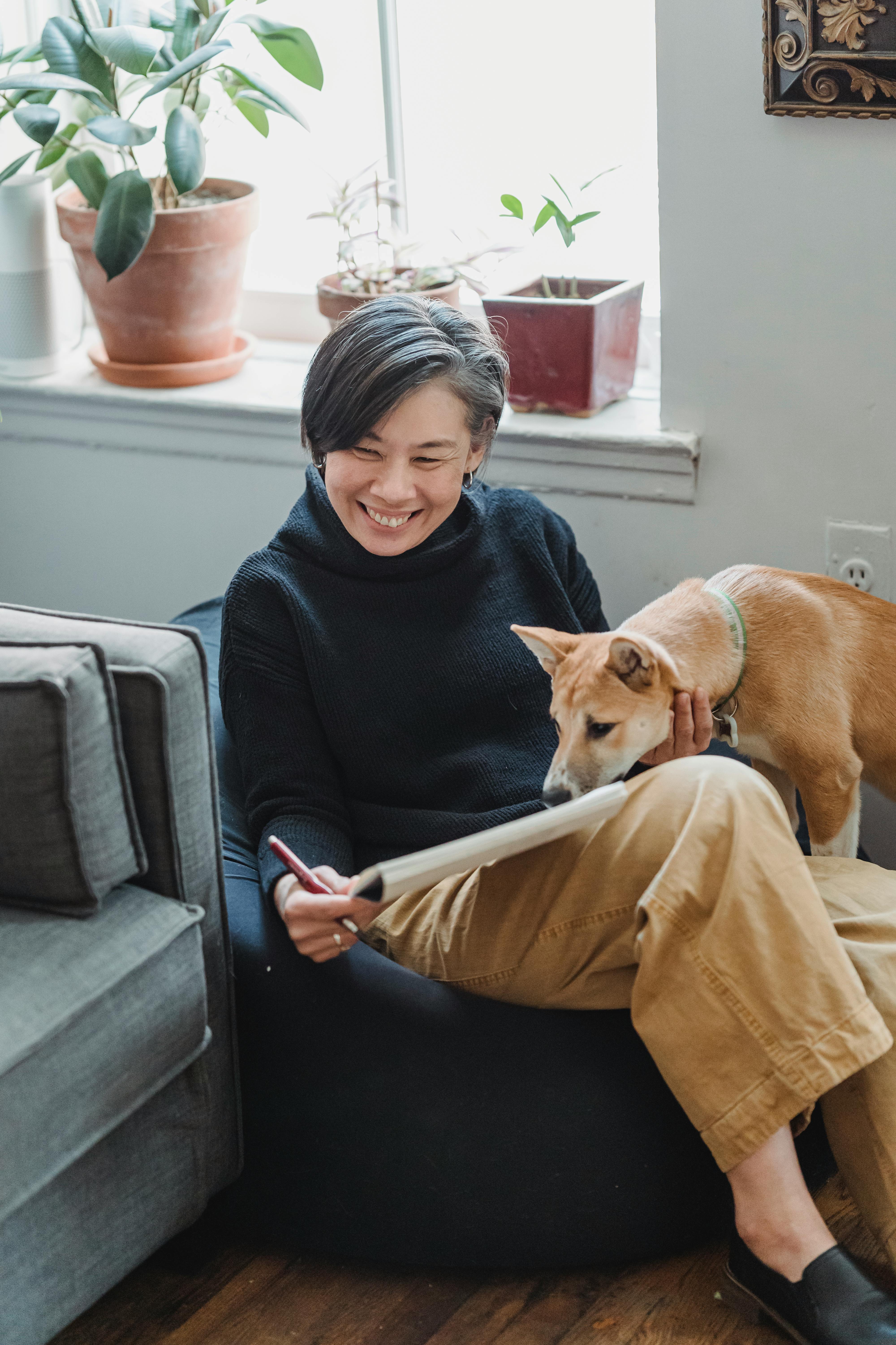 Smiling woman enjoys quality time with her loyal dog indoors. Cozy and joyful atmosphere.