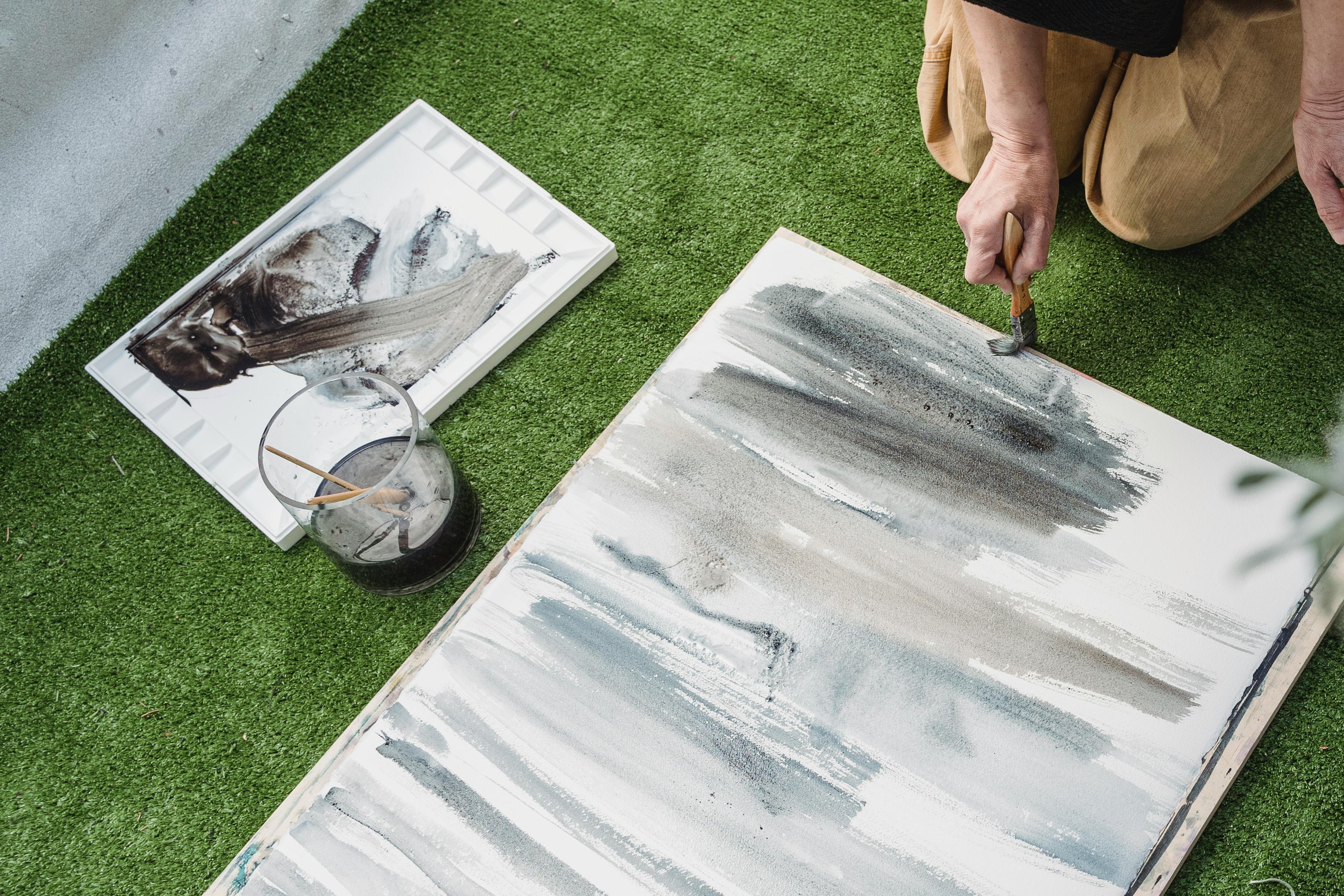 Pessoa praticando aquarela em casa com pincel e paleta de cores