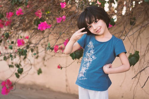 無料 ピンクの花びらの花の横にある青いクルーネックtシャツの女の子 写真素材