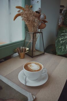 Warm espresso with latte art on a stylish coffee table by a window with rustic decor.