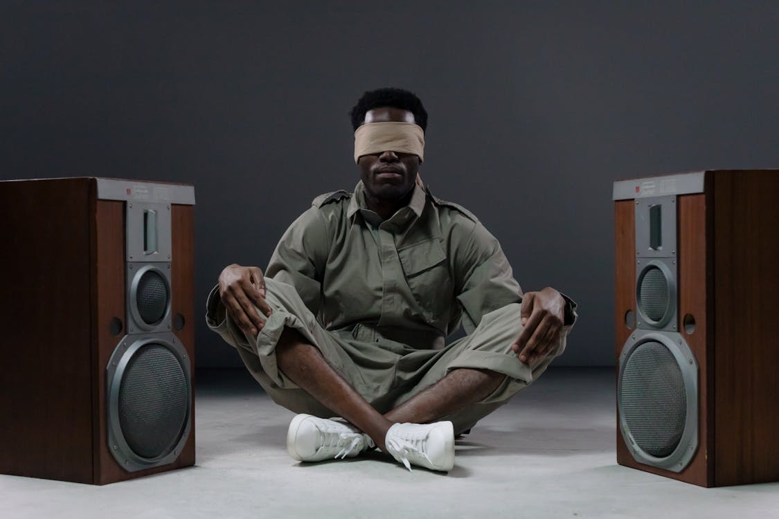 Free Man with Blindfold Sitting on the Floor with Speakers Stock Photo