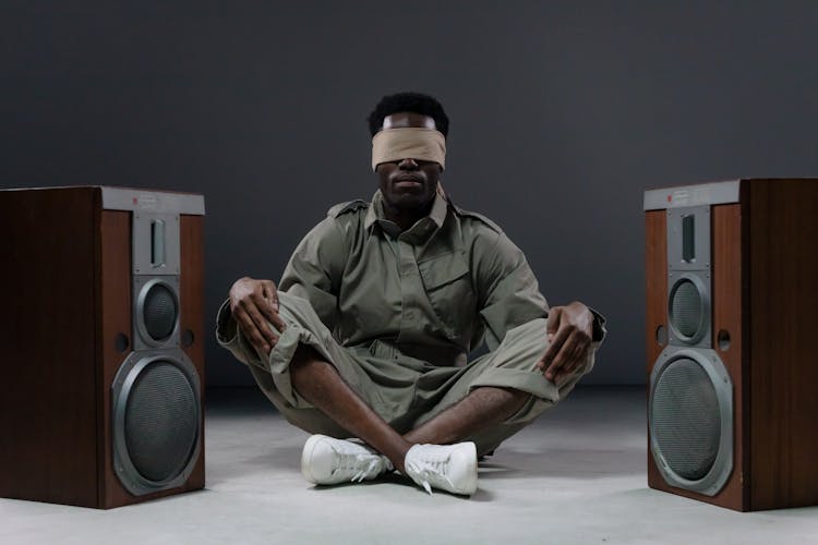 Man With Blindfold Sitting On The Floor With Speakers