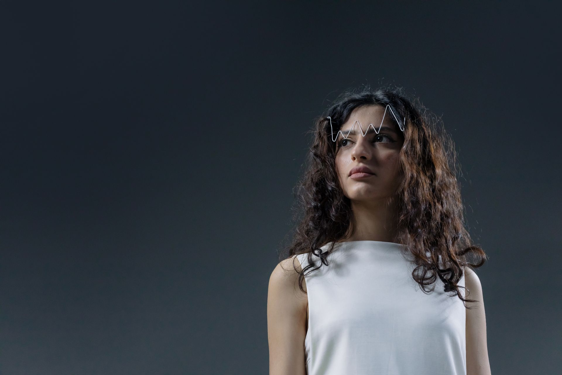 Studio portrait of a woman with curly hair and abstract eyewear, serene expression.