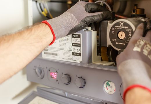 Hands adjusting a home boiler's controls
