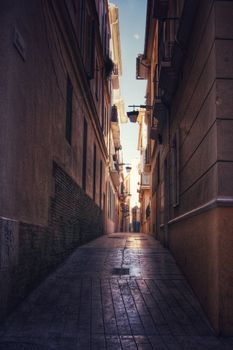 Explore a serene, narrow alleyway between historic buildings in a quaint European city, exuding charm and ambiance.