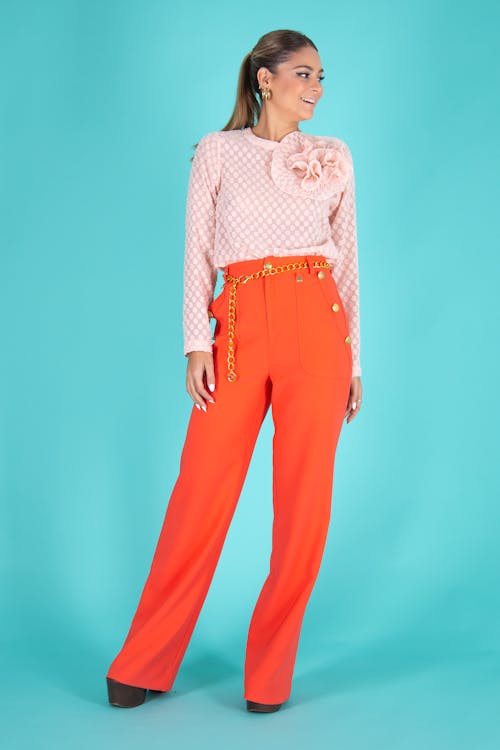 A Woman in Orange Pants Standing while Smiling